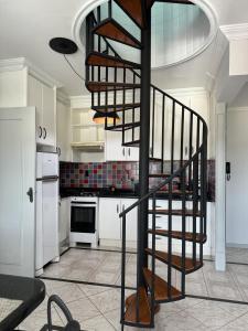 uma escada em espiral numa cozinha com armários brancos em Duplex Ametista em Gravatal
