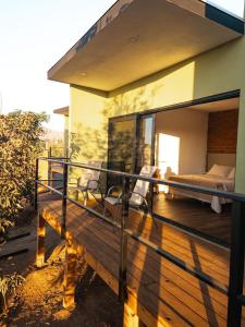 a balcony of a house with a bed and chairs at Palta 60 Valle de Guadalupe in Valle de Guadalupe