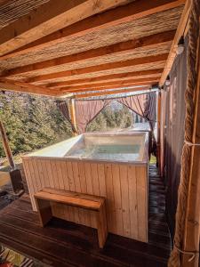 Zagórnik的住宿－Aloha Glamp - Domki z prywatnym jacuzzi & balia & sauna，一座带木屋顶的建筑中的热水浴缸