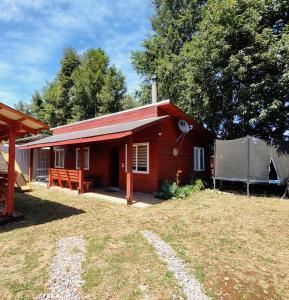 a small red house with a large yard at Cabaña entre rios in Villarrica