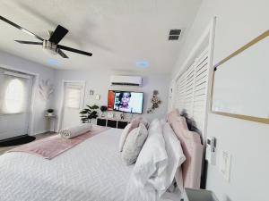 a white bedroom with a bed and a tv at Modern Dream Rooms Suits - Private, parking, Wi-Fi, Netflix in Spring Hill