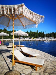a group of lounge chairs under an umbrella on a beach at Apartment Michaela 4-Sterne & Parking in Rovinj