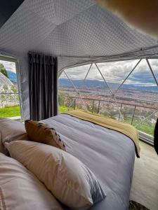 a bed in a tent with a large window at NaturHotel in Cuenca