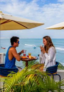 a man and a woman sitting at a table in front of the ocean at Vila Gallina Pousada in Jericoacoara