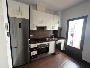 eine Küche mit weißen Schränken und einem Kühlschrank aus Edelstahl in der Unterkunft Bonito apartamento en Utrera WIFI gratis in Utrera