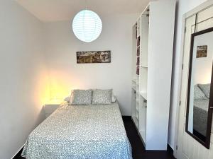 ein kleines Schlafzimmer mit einem Bett und einer Lampe in der Unterkunft Bonito apartamento en Utrera WIFI gratis in Utrera