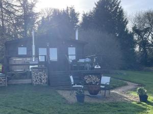 a log cabin with a table and chairs in a yard at Cosy cabin in Annie’s meadow in West Meon