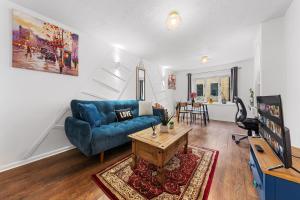 a living room with a blue couch and a table at Quirky Canary 2Bed, Free Parking, Smart TV & Games in London