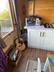 una cocina con una guitarra en una casa pequeña en Cosy cabin in Annie’s meadow en West Meon