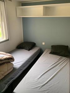 2 camas individuales en una habitación con ventana en Mobil-home Ouistreham, en Ouistreham