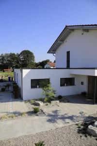 ein weißes Haus mit einer Terrasse davor in der Unterkunft Wohnen am Bach in Haiming