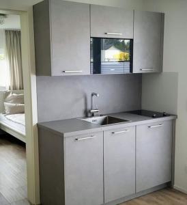 eine Küche mit weißen Schränken, einem Waschbecken und einem Bett in der Unterkunft Wohnen am Bach in Haiming
