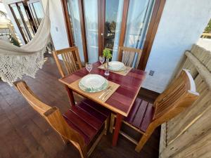 una mesa de madera con platos y vasos en el balcón en Jurema Branca Villa, en Beberibe