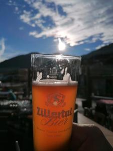a person holding a glass of beer with the sun in the background at Ferienwohnung Birkenheim in Fügenberg