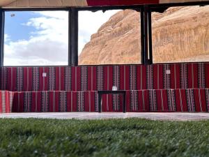 a room with red walls with a table and grass at wadi rum caeser camp in Wadi Rum