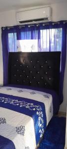 a bedroom with a bed with a black headboard and purple curtains at Bethel in La Viva