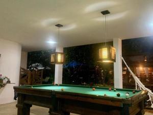 a pool table in a living room with two lights at Espaço Hale Kai in Guarapari