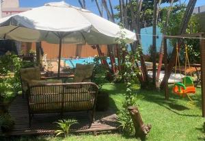 a patio with an umbrella and chairs and a pool at Espaço Hale Kai in Guarapari