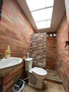 a brick bathroom with a toilet and a sink at Finca los Juanes in Jardin