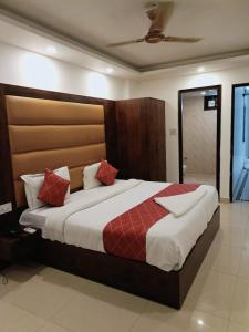 Hotel Tej Plaza Near IGI Airport في نيودلهي: غرفة نوم بسرير كبير ومخدات حمراء
