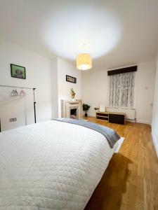 a bedroom with a large white bed and a fireplace at LA CASITA in Colindale