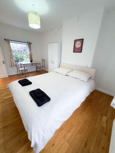 a large white bed in a room with a wooden floor at LA CASITA in Colindale