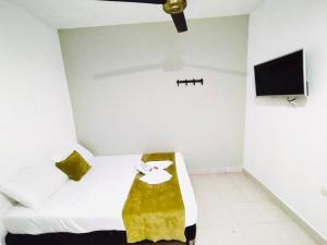 um quarto branco com uma cama e uma televisão em Laurel plaza em Montería