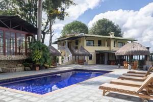 a villa with a swimming pool and a house at El Edén Country hotel y Club Residencial in Armenia