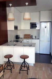 a kitchen with two bar stools and a refrigerator at Appartement résidence neuve proche Versailles in Saint-Cyr-lʼÉcole