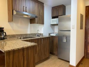 a kitchen with wooden cabinets and a stainless steel refrigerator at Apartamentos La Cañada in Guatemala