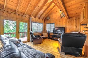 a living room with a leather couch and a television at Cozy Mi-Wuk Village Cabin 18 Mi to Dodge Ridge! in Mi-Wuk Village