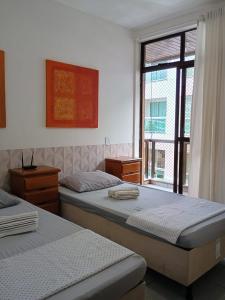 1 dormitorio con 2 camas y ventana grande en Apartamento charmoso em frente a praia em Cabo Frio, en Cabo Frío