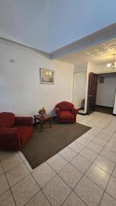 ein Wohnzimmer mit 2 roten Stühlen und einem Tisch in der Unterkunft Hotel Valladolid in Heredia