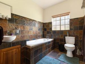 a bathroom with a tub and a toilet and a sink at Lilly’s-place in Sabie