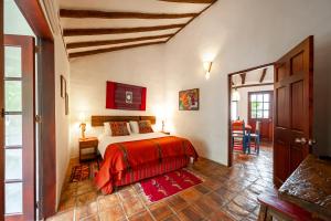 1 dormitorio con 1 cama con manta roja en Casa de Las Aguas, en Villa de Leyva