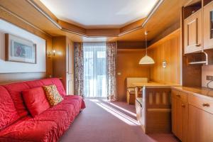 a living room with a red couch and a kitchen at Appartamenti Sausalito in Selva di Val Gardena