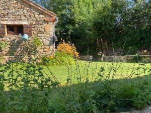 a garden with a stone building and a yard with grass at A l'Orée des Vignes in Sauveterre-la-Lémance