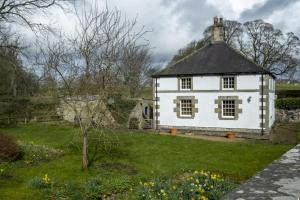 uma antiga casa branca com um telhado preto em White Lodge Haughton Castle em Hexham