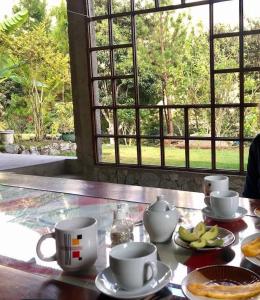 una mesa con tazas y platos de comida y una ventana en Lucmabamba Lodge, en Santa Teresa