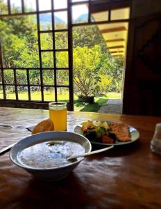 una mesa con un plato de comida y un vaso de zumo de naranja en Lucmabamba Lodge, en Santa Teresa