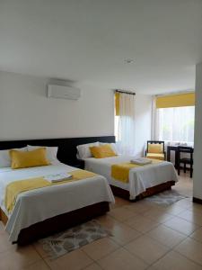 1 dormitorio con 2 camas con almohadas amarillas y mesa en Hotel Yurak en Archidona