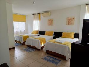 Habitación con 3 camas con sábanas amarillas. en Hotel Yurak en Archidona