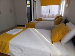two beds in a room with yellow pillows at Hotel Yurak in Archidona
