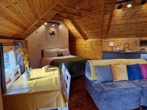 a room with a bed and a couch in a cabin at The Hive - Unique log cabin with wood burning stove in Ludchurch