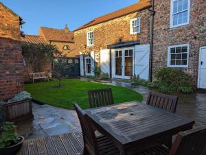 a patio with a wooden table and chairs in a yard at Skipton House Annex in Thirsk