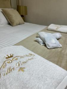 two beds with white sheets and gold embroidered towels at Villa laura in Palermo