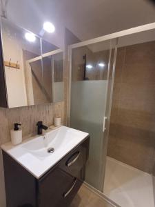 La salle de bains est pourvue d'un lavabo blanc et d'une douche. dans l'établissement Super F2 à 5mn aéroport d'Orly, à Paray-Vieille-Poste