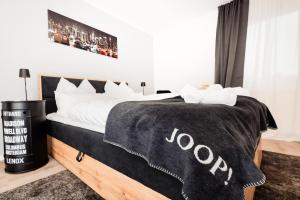 a bed with a black and white blanket on it at bee Apartments Design NESPRESSO Küche Parkplätze PS5 in Aachen