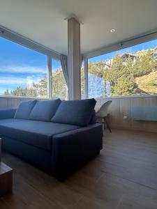 a living room with a blue couch and large windows at Primavera Premium Sierra Nevada 4 in Sierra Nevada