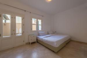 a white bedroom with a bed and a window at Abutig Marina flat ground floor in Hurghada
